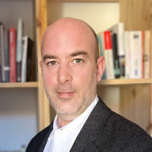 Le journaliste Simon Icard - Portrait devant une bibliothèque.